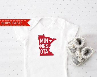 May include: White baby onesie with a red outline of the state of Minnesota and the text "MINNESOTA" with a red heart in the middle of the state.