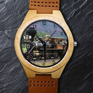 May include: A wooden wristwatch with a brown leather strap. The watch face features a vintage steam locomotive with a black and brown colour scheme. The numbers 1 through 12 are displayed around the edge of the watch face.