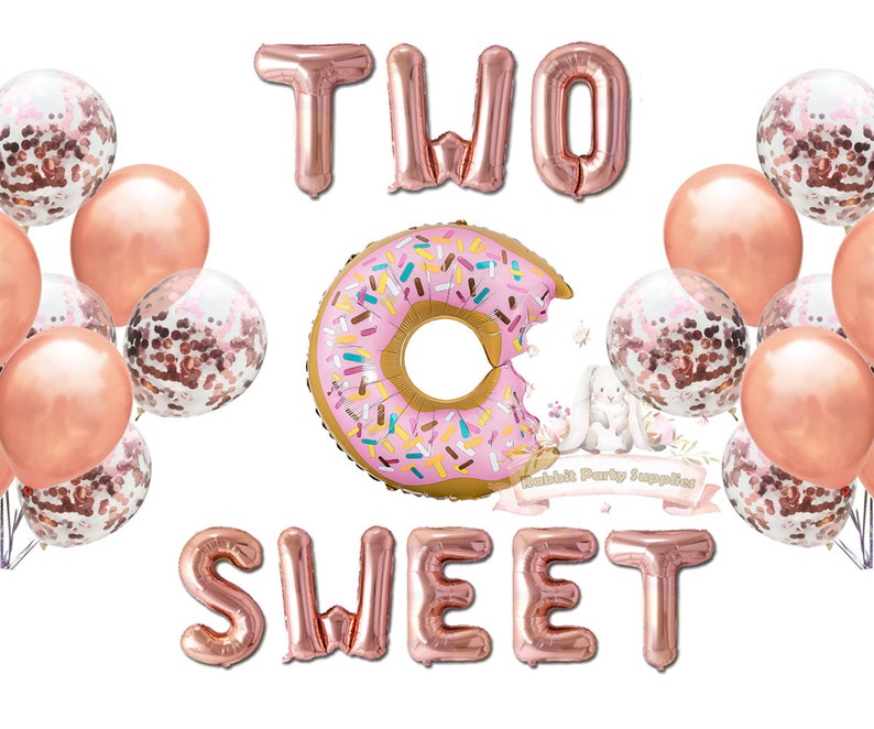 Op de afbeelding: Een verzameling feestballonnen in roze en ros&eacute;goud. De opstelling bevat de woorden "TWO SWEET" in folieballonnen, een donutvormige ballon en met confetti gevulde ballonnen. Perfect voor een tweede verjaardag.