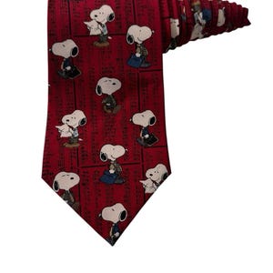 以下が含まれることがあります： スヌーピーのキャラクターが繰り返し描かれた赤いネクタイ。ネクタイはクラシックな形で、滑らかな生地で作られています。スヌーピーのキャラクターは白、黒、茶色です。