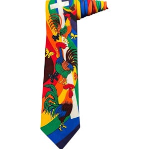May include: A necktie featuring a vibrant rainbow background with a white cross at the top. The design includes three colorful roosters in various poses, interspersed with small black and yellow butterflies. The top of the tie is rolled up.
