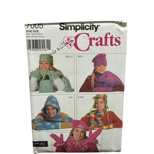 Puede incluir: Un sobre de patrón Simplicity Crafts con imágenes de gorros, bufandas y guantes. El sobre tiene el texto "Simplicity Crafts" y "7005". Las imágenes muestran diferentes estilos de gorros y bufandas en varios colores.