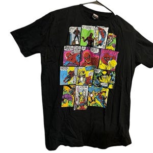 May include: A black short-sleeve t-shirt featuring a multi-panel comic book graphic print on the front. The graphic displays various scenes with Spider-Man and Wolverine, including action text bubbles that read BRRAKK and WOK.