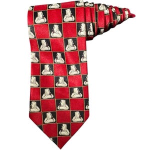 May include: Red necktie with a repeating pattern of polar bears in black and white squares. The bears are holding a bottle. The tie is folded and has a pointed end.