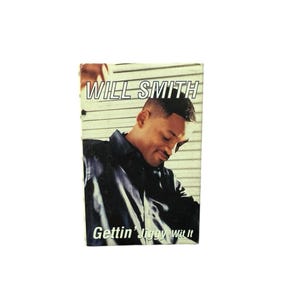 Könnte beinhalten: Ein kleines, rechteckiges Bild mit Will Smith. Der Text "WILL SMITH" steht oben, darunter "Gettin' Jiggy Wit It". Smith trägt ein schwarzes Hemd und blickt nach unten.