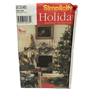 Puede incluir: Una caja de colección de patrones Simplicity Holiday. La caja es roja y blanca con la palabra "Holiday" en letras grandes. La caja presenta una imagen de un árbol de Navidad decorado y una chimenea. También es visible el texto "ONE SIZE" y "UNE SEULE TAILLE".