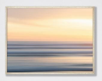 May include: A framed abstract photograph of a blurred sunset over a body of water. The colors are soft and muted, with shades of pink, orange, and blue.