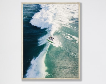 Può includere: Un surfista cavalca un'onda, prendendo il volo mentre incide una curva. L'onda è di un blu turchese brillante, con la schiuma bianca che cresta in cima. Il surfista indossa una muta da surf nera e una tavola da surf verde.