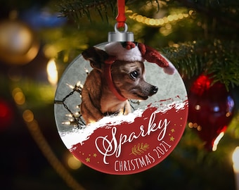 Peut inclure: Une boule de Noël rouge et blanche avec une photo d'un chihuahua brun et blanc portant un chapeau de Père Noël. La boule est ornée du texte "Sparky Noël 2021".
