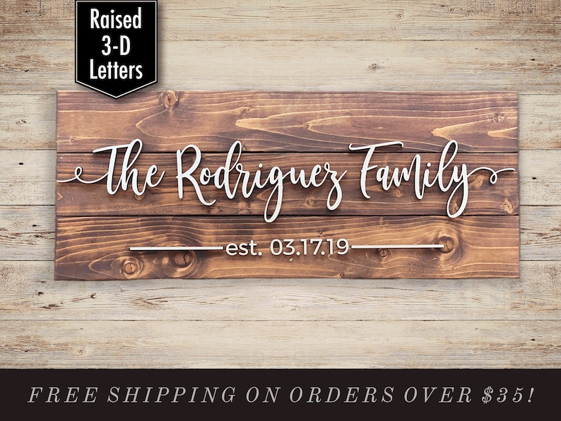 Puede incluir: Un letrero de madera con el texto "The Rodriguez Family est. 03.17.19" en letras blancas en 3D en relieve. El letrero tiene un acabado de madera r&uacute;stica marr&oacute;n.