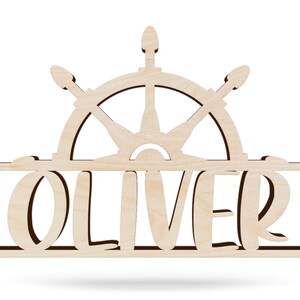 May include: Wooden name sign with the name "OLIVER" in a decorative font. The name is centered below a wooden ship's wheel.