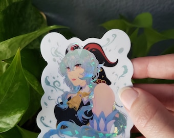 Pode incluir: Um adesivo holográfico com um personagem de cabelo azul longo, uma faixa de cabeça vermelha e um traje preto e azul. O personagem está rodeado por desenhos azuis e brancos que giram.