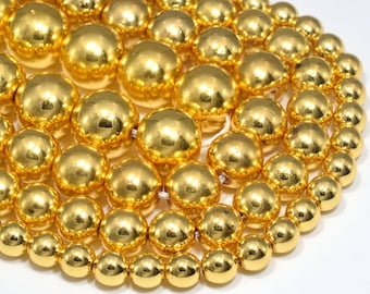 Könnte beinhalten: Eine Strähne runder, goldfarbener Perlen. Die Perlen sind glatt und glänzend und in einem Kreis angeordnet.