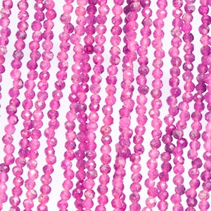 May include: Strands of faceted, hot pink gemstone beads. The beads are small, round, and strung together, creating a vertical pattern against a white background. The beads have a sparkling, polished appearance, suggesting they are made of a precious stone.