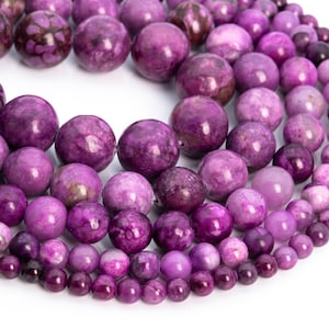 May include: A strand of purple gemstone beads, with varying sizes and shades of purple. The beads are round and smooth, with a marbled pattern.