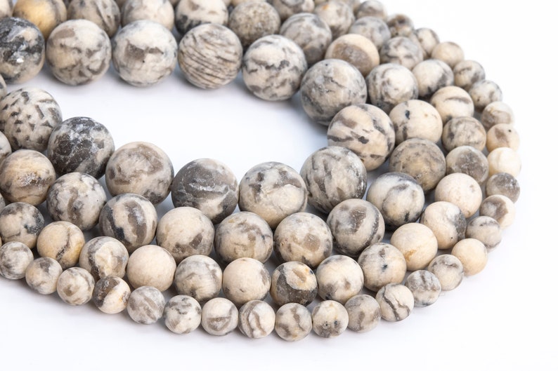 May include: A strand of round, white and gray agate beads with a marbled pattern. The beads are strung together on a clear thread.