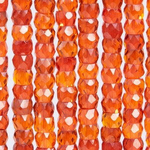 May include: A strand of faceted orange glass beads. The beads are round and have a smooth, polished finish.