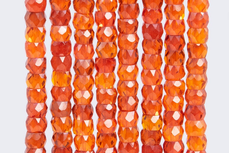 May include: A strand of faceted orange glass beads. The beads are round and have a smooth, polished finish.