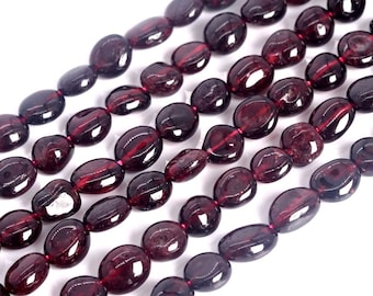 May include: Five strands of polished, deep red garnet beads arranged in parallel rows. Each strand consists of smooth, oval-shaped stones with a glossy finish, strung together on a thin, dark red cord, showcasing natural variations in color.