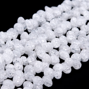 May include: A strand of white, clear, faceted, oval-shaped beads. The beads have a rough, textured surface.