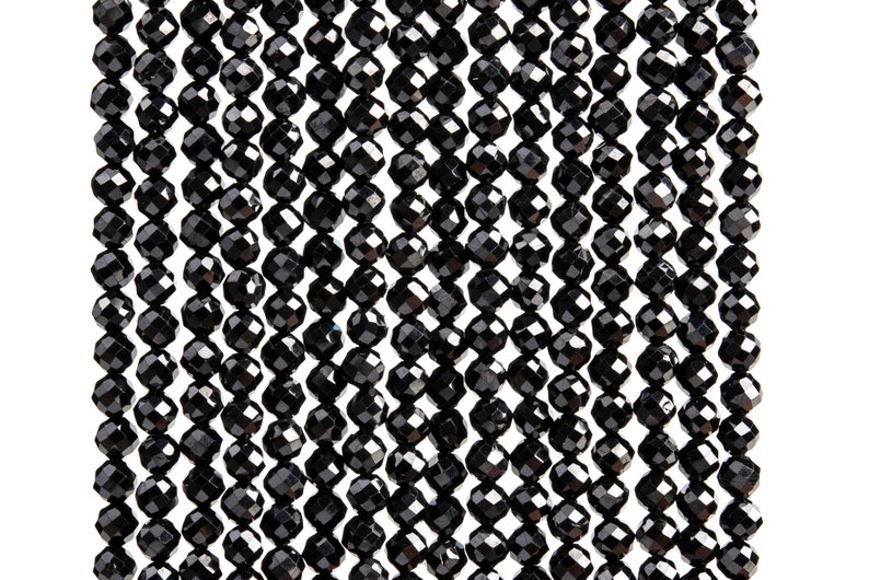 May include: A strand of black faceted gemstone beads. The beads are round and have a shiny finish.
