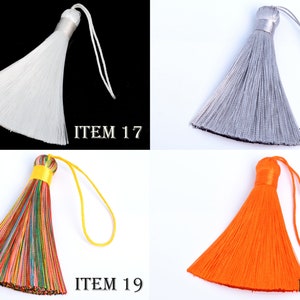 May include: Four decorative tassels in white, silver, multicolored, and orange. Each tassel has a loop for hanging and a decorative top. The image includes the text "ITEM 17", "ITEM 18", "ITEM 19", and "ITEM 20".