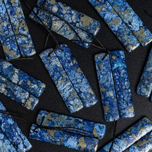 May include: A set of 10 blue and gold stone pendants with black cords. The stones have a marbled pattern with blue and gold flecks.