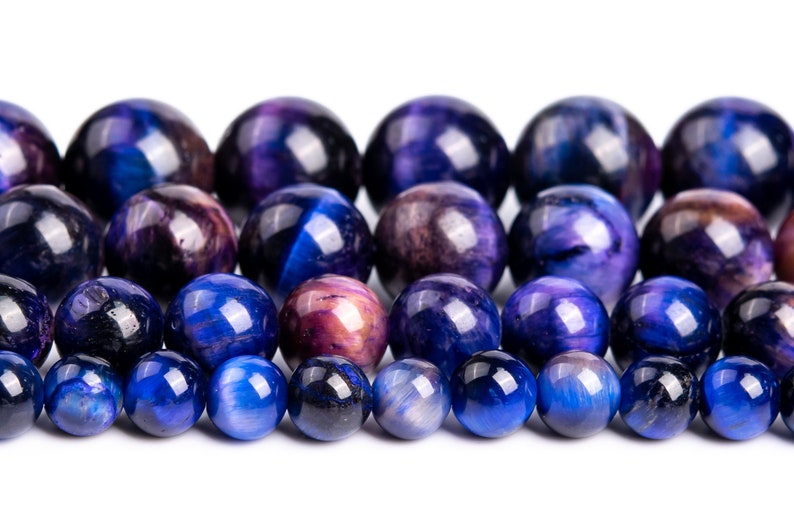 Peut inclure: Un brin de perles en &oelig;il de tigre bleu et violet. Les perles sont rondes et lisses, avec une finition brillante.