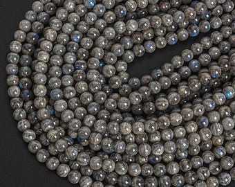 May include: A strand of dark gray labradorite gemstone beads. The beads are round and smooth, with a slight iridescent sheen.