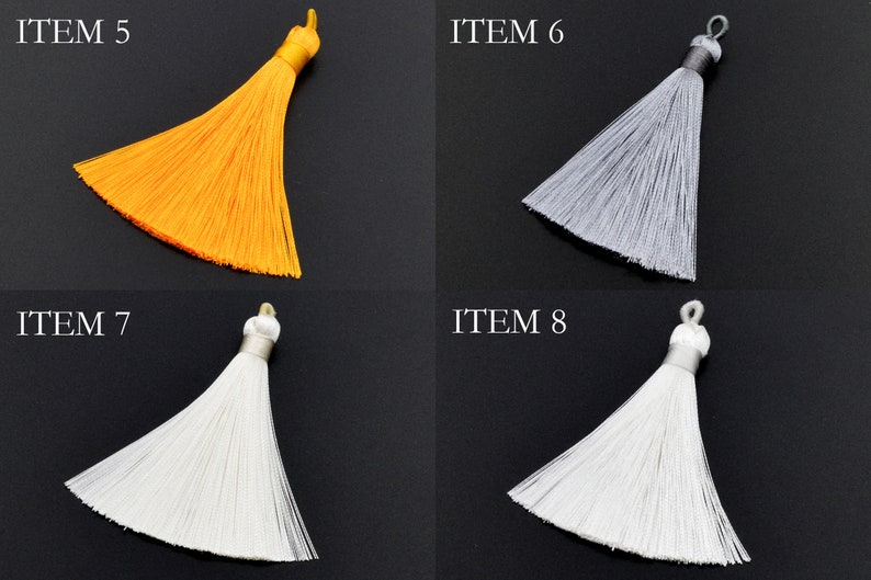 May include: Four different colored tassels, each with a loop at the top. The tassels are yellow, gray, white, and white. The tassels are labeled "ITEM 5", "ITEM 6", "ITEM 7", and "ITEM 8".