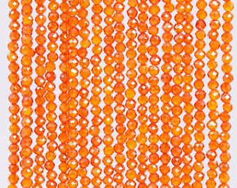 May include: A strand of orange carnelian beads, each bead is faceted and has a round shape. The beads are strung on a clear thread.