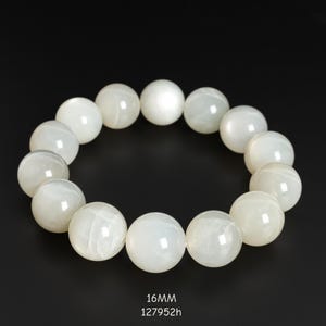 May include: A white beaded bracelet with large, round beads. The bracelet is displayed against a black background. The text "16MM" and "127952h" is at the bottom of the image.