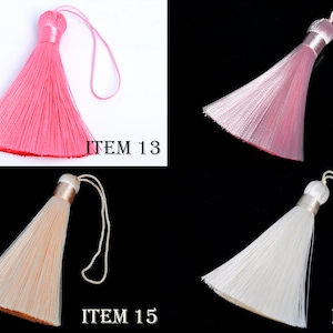 May include: Four decorative tassels in pink, light pink, cream, and white. Each tassel has a looped string for hanging and a cylindrical top. The image includes the text "ITEM 13", "ITEM 14", "ITEM 15", and "ITEM 16".