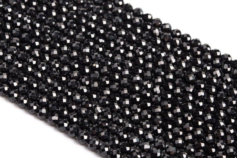 May include: A strand of black faceted beads. The beads are small and round, with a shiny finish.
