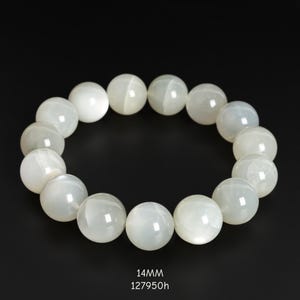 May include: A bracelet featuring large, round, off-white beads. The beads have a pearlescent sheen and are strung together to form a circular shape. The text "14MM" and "127950h" is at the bottom of the image.