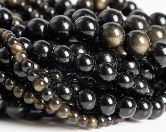 Puede incluir: Una colección de cuentas de obsidiana dorada pulidas y esféricas dispuestas en múltiples hilos. Las cuentas son principalmente negras con inclusiones metálicas de color dorado reflectante que brillan bajo la luz, variando en tamaño entre los hilos.