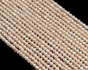 May include: A strand of translucent, faceted, light peach-colored glass beads. The beads are round and have a slight shimmer.