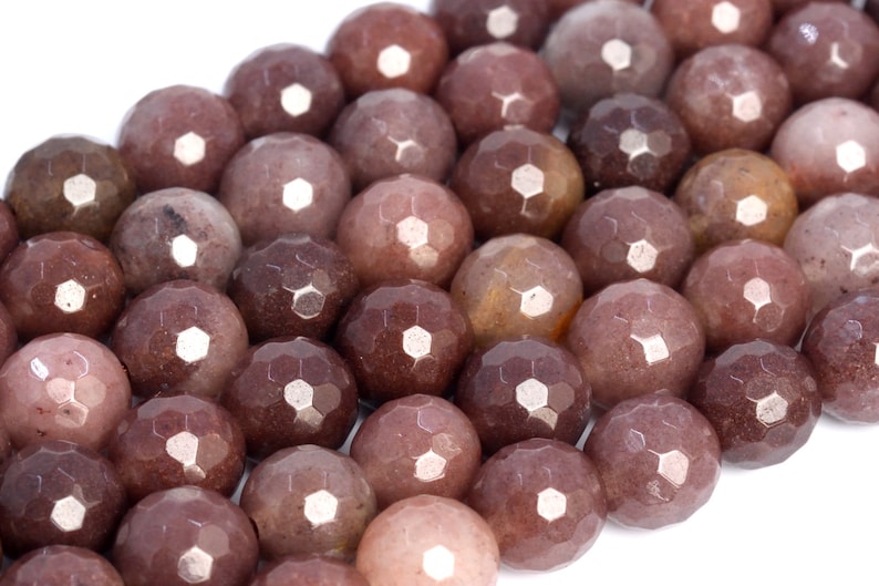 Puede incluir: Una hebra de cuentas de piedras preciosas facetadas en tonos marrones y rosados. Las cuentas son redondas y tienen un acabado liso y pulido.