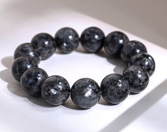 May include: A stretch bracelet composed of thirteen large, spherical beads made of dark gray labradorite stone. Each bead features a polished, reflective surface with natural mottled patterns and subtle variations in tone throughout the stone.