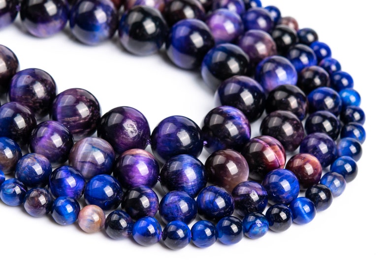 Peut inclure: Un collier de perles en &oelig;il de tigre bleu et violet. Les perles sont rondes et ont une finition lisse et polie. Les perles sont enfil&eacute;es sur un cordon &eacute;lastique transparent.