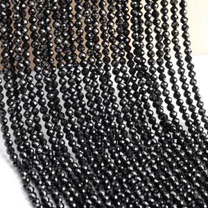 May include: A strand of black faceted beads, likely made of black spinel or black diamond, for jewelry making.
