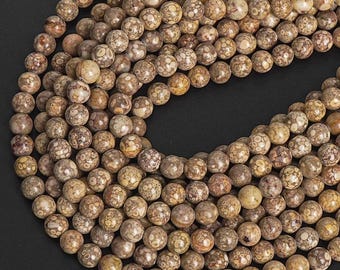 May include: A close-up shot of a collection of round, natural stone beads. The beads are primarily tan and brown with a speckled pattern. The beads are strung together, suggesting they are for jewelry making or crafts.