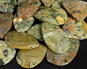 May include: A collection of polished gemstones in shades of green, brown, and yellow. The stones have a natural, organic appearance with unique patterns and textures. Some stones have a hole drilled through them.