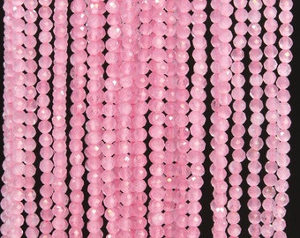 Puede incluir: Primer plano de múltiples hebras de cuentas facetadas de color rosa claro. Las cuentas están ensartadas, creando un efecto de cascada. Las cuentas tienen una calidad brillante y translúcida, y están colocadas sobre un fondo negro. Ideal para la fabricación de joyas.