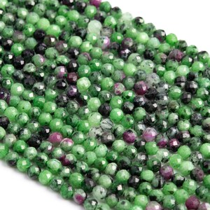 May include: A strand of green, black, and pink faceted gemstone beads. The beads are round and have a smooth, polished finish.
