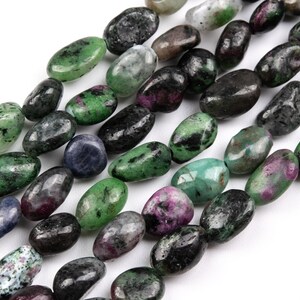May include: A strand of green, black, and pink gemstone beads. The beads are smooth and oval-shaped.