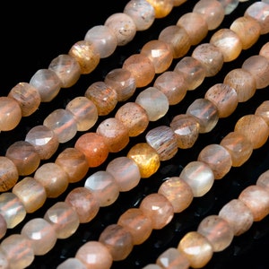 May include: A strand of faceted sunstone beads in shades of peach, orange, and gold. The beads are faceted and have a shimmery, iridescent finish.