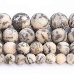 May include: A strand of round, white and gray agate beads. The beads have a mottled, marbled pattern.