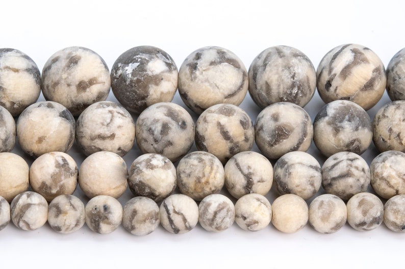 May include: A strand of round, white and gray agate beads. The beads have a mottled, marbled pattern.