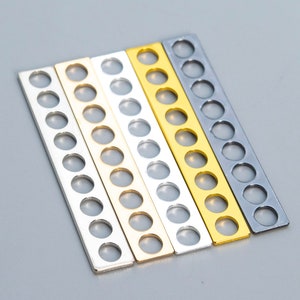 May include: Four metal strips with round holes, in black, silver, gold, and a lighter gold color.